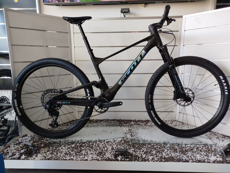 E-MTB da trail full-suspension Megamo Reason Air CRB 10 2026 in colorazione blu. Vista laterale del telaio leggero interamente in carbonio con escursione da 140 mm. In evidenza il potente motore centrale DJI Avinox, la batteria integrata da 800 Wh, la forcella Fox da 140 mm, la trasmissione Shimano XT a 12 velocità e le ruote da 29 pollici