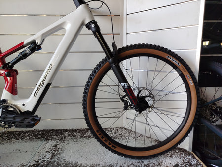 E-MTB biammortizzata Megamo Reason AL 07 nella colorazione White Red (bianco e rosso). Il telaio in alluminio idroformato mostra una sfumatura dal bianco anteriore al rosso bordeaux posteriore. In evidenza il motore DJI Avinox, la batteria integrata, la forcella Fox e le ruote da 29 pollici per e-mountain bike
