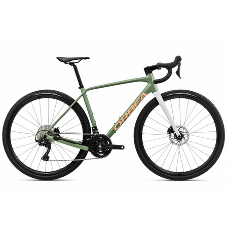 Bicicletta gravel Orbea Terra H30 in colorazione Infinity Green lucido con dettagli Ivory White. Inquadratura laterale del telaio in alluminio idroformato a triplo spessore e forcella in carbonio con passaggio cavi integrato ICR. Visibili il gruppo Shimano GRX a 12 velocità, i freni a disco idraulici e i pneumatici tassellati da gravel.